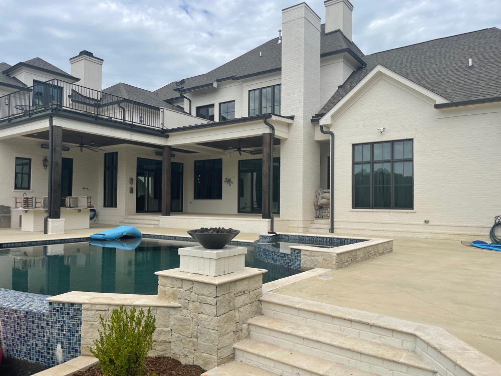 Pool deck at a Brentwood estate stained an even, warm cream tone and sealed, running from the covered porch out to the steps