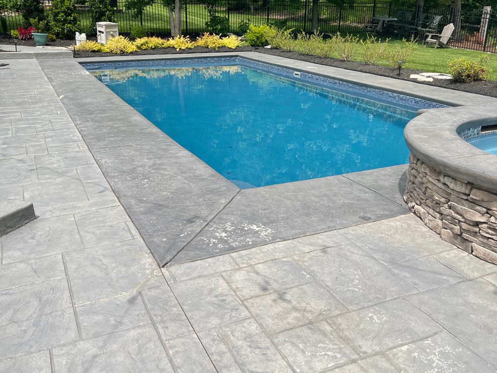 The same Brentwood pool deck before resurfacing, the stamped ashlar faded to a cold, blotchy gray