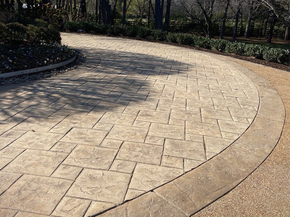Curved stamped approach to a Brentwood motor court resurfaced to a warm tan, the running-bond pattern still crisp through the sweep