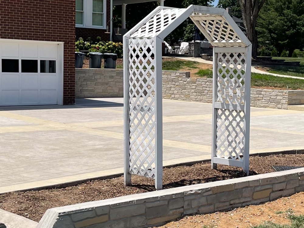 Replacement concrete driveway at a Franklin home, poured square to the brick garage with cut control joints and a curbed edge along the planting bed