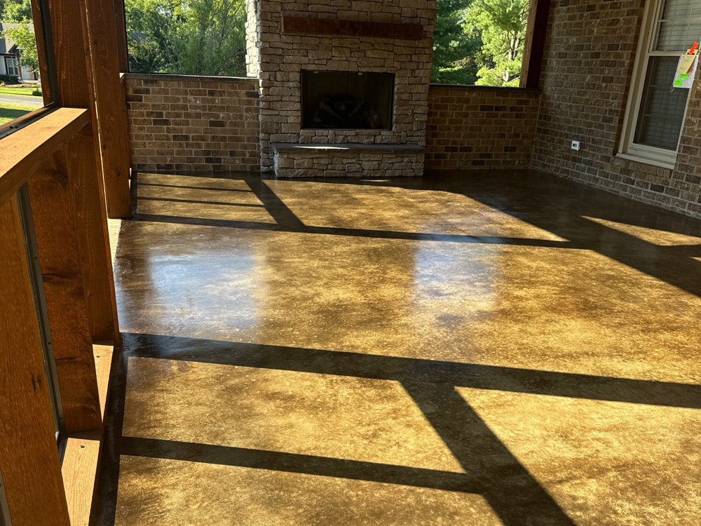 Covered outdoor living space in Franklin with a stone fireplace, the floor stained a mottled amber and sealed to a gloss