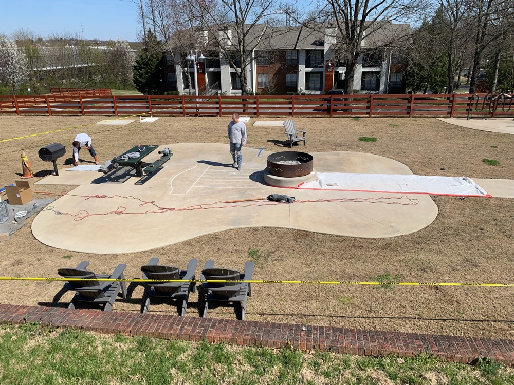 The same Nashville patio before staining, a bare gray guitar-shaped slab around a fire pit